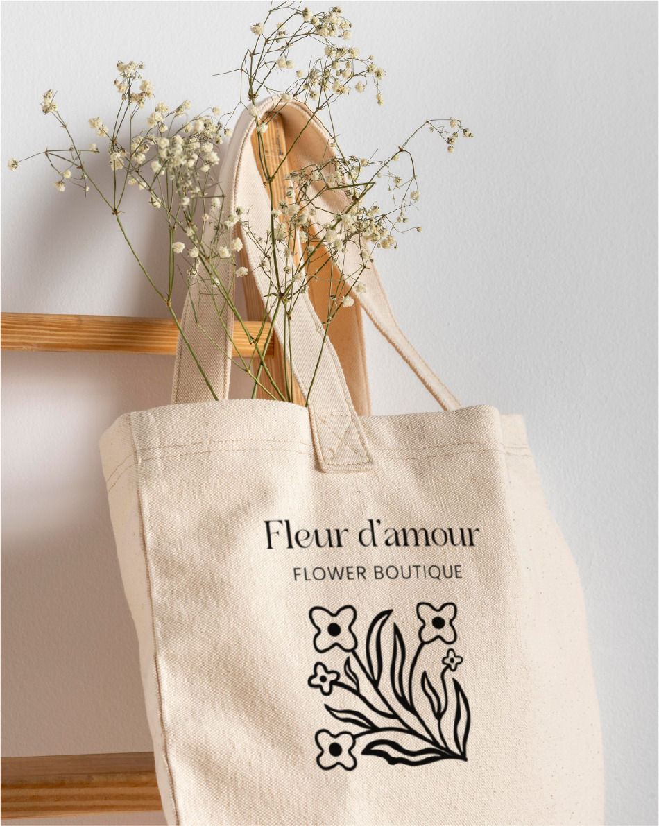 image of hanging tote bag with flowers and fleur d'amour logo in the center